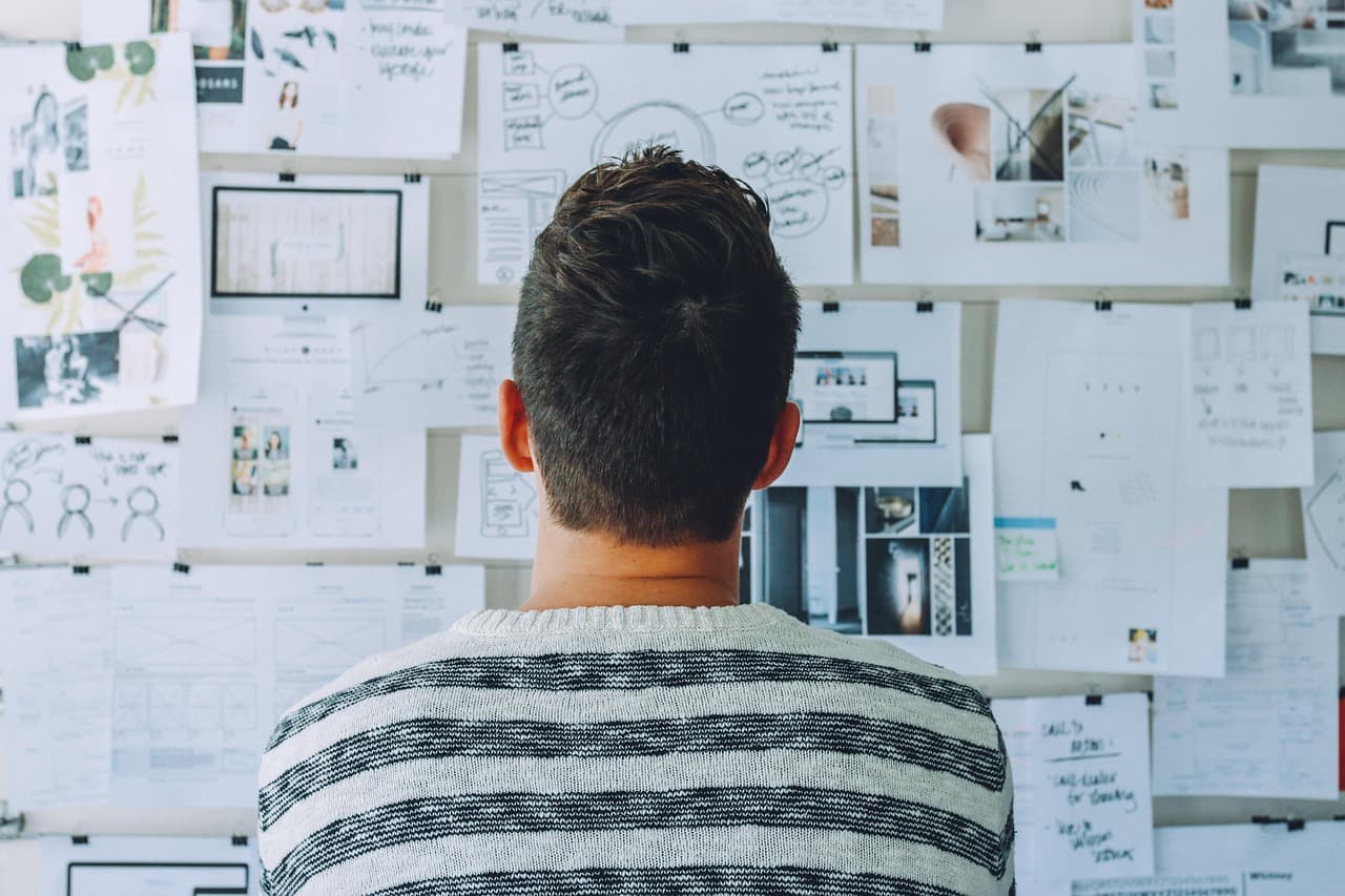 A small business owner sitting at a desk working on a laptop while checking notifications on a smartphone, representing the challenge of managing multiple customer communication channels simultaneously.